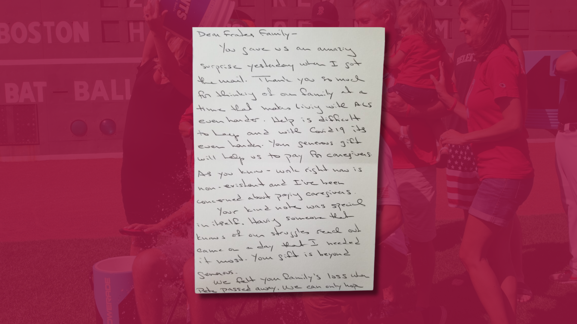 A handwritten letter is displayed in the foreground, with people standing and a red media backdrop showing partially visible text and graphics in the background.